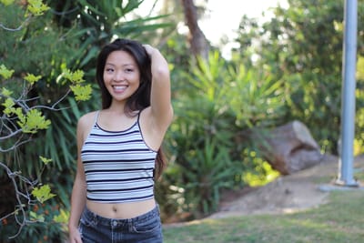 Lifestyle portrait smiling in a striped top against tropical greenery