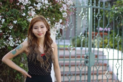 Close outdoor portrait by a flowering bush and garden gate